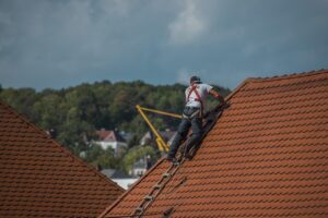 couvreur équipé, effectuant un travail d'entretien d'une toiture de maison traditionnelle