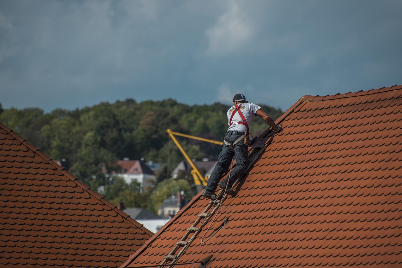 couvreur équipé, effectuant un travail d'entretien d'une toiture de maison traditionnelle